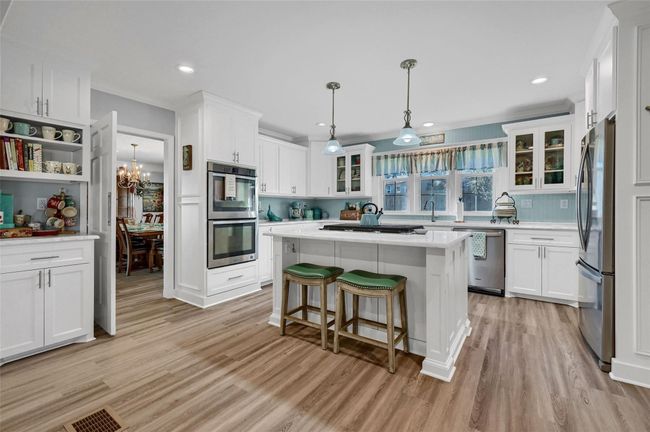 Kitchen featuring appliances with stainless steel finishes, light wood-style floors, light countertops, white cabinetry, and recessed lighting | Image 17