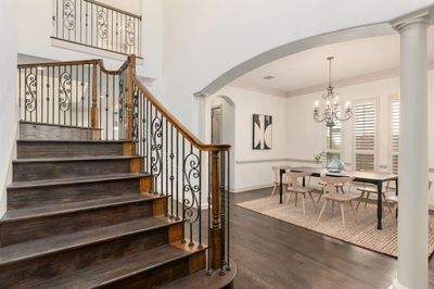 Staircase featuring dark wood-type flooring, crown molding, a notable chandelier, and decorative columns | Image 3