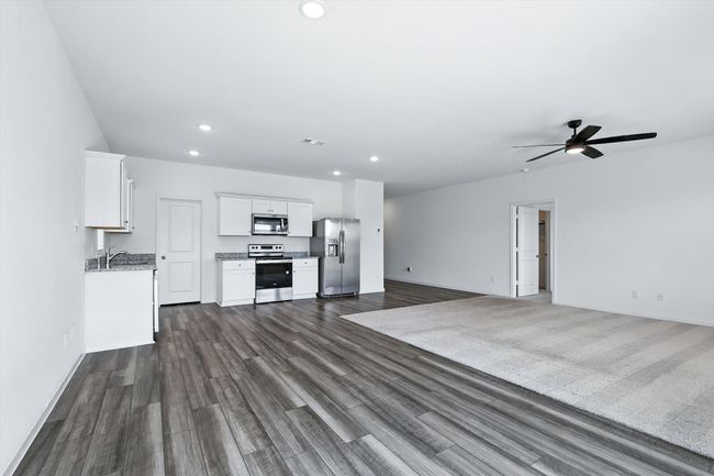 Kitchen with open floor plan, appliances with stainless steel finishes, white cabinetry, recessed lighting, and dark wood finished floors | Image 6