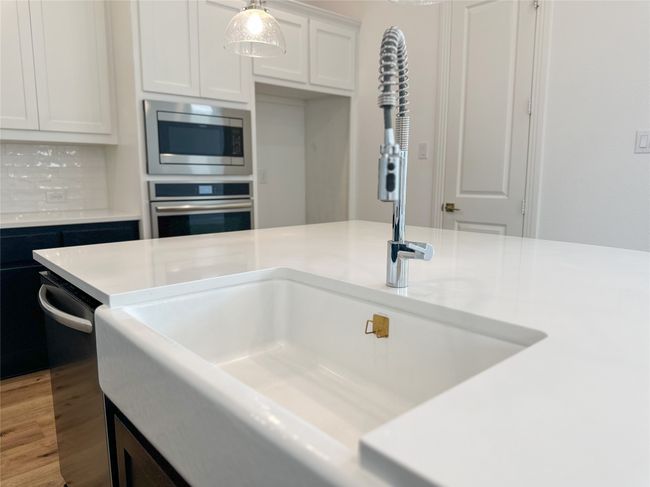 Kitchen featuring appliances with stainless steel finishes, light countertops, light wood-style flooring, and white cabinetry | Image 15