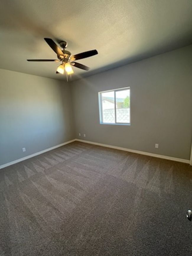 Unfurnished room with baseboards, dark colored carpet, and ceiling fan | Image 9