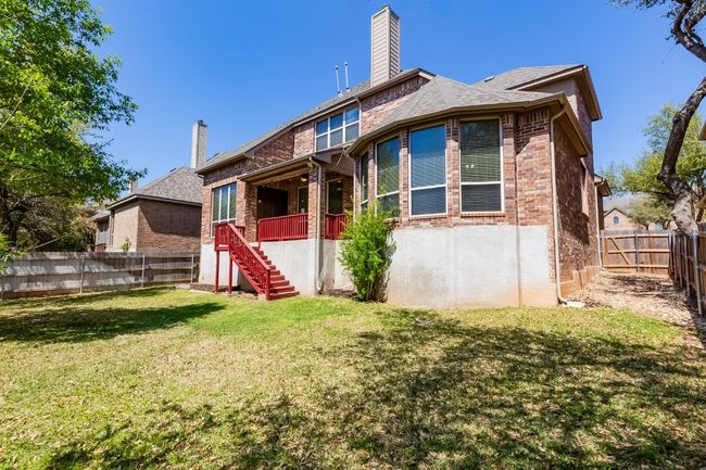 Back of house featuring stairs, a fenced backyard, brick siding, a yard, and a chimney | Image 37