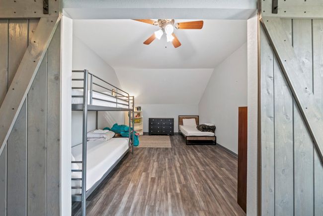 Bedroom with lofted ceiling, wood finished floors, and a barn door | Image 28