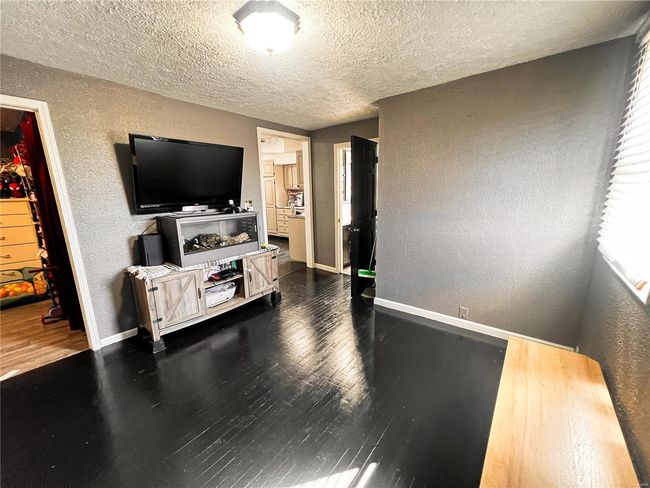 Living area with dark wood-style flooring, a textured wall, a textured ceiling, and baseboards | Image 13