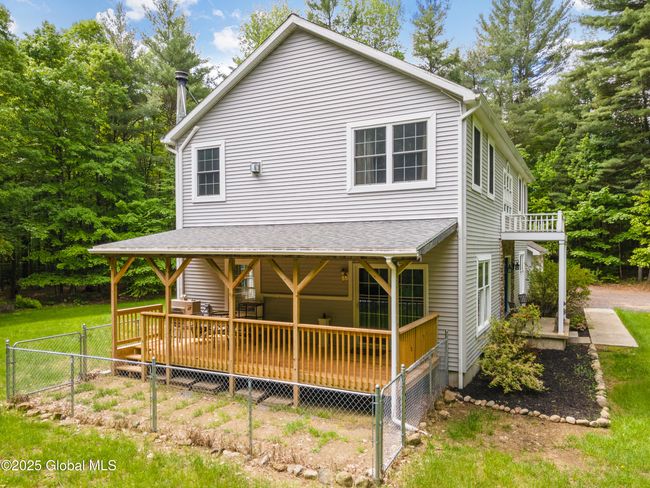Side view of house featuring newer covered deck, built in 2024 and fenced in dog-run or vegetable garden | Image 40