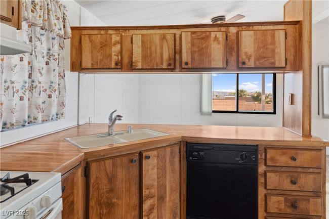 Kitchen featuring a sink, brown cabinetry, dishwasher, and light countertops | Image 13