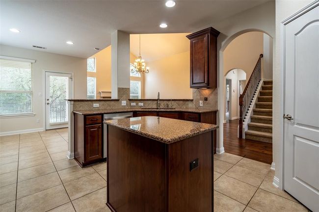 Kitchen with a kitchen island, light tile patterned floors, decorative backsplash, dark stone counters, and lofted ceiling | Image 6