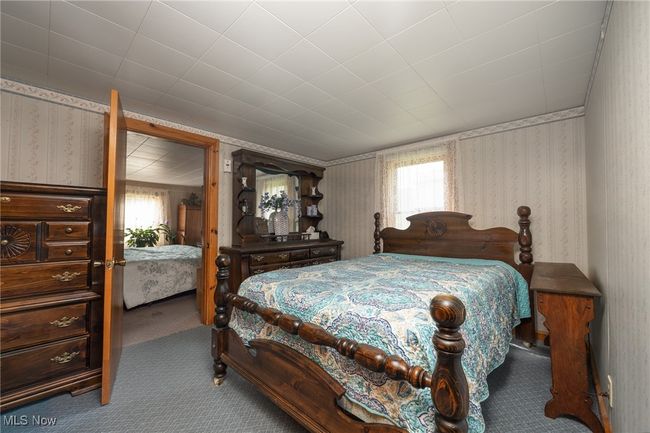 Carpeted bedroom with wallpapered walls and multiple windows | Image 17