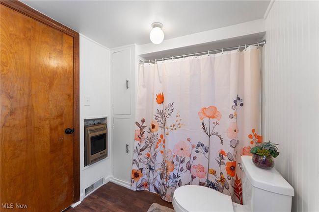 Bathroom with heating unit, wood finished floors, and a shower with curtain | Image 14