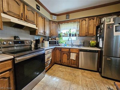 Kitchen featuring decorative backsplash, stainless steel appliances, light tile patterned floors, and ornamental molding | Image 3