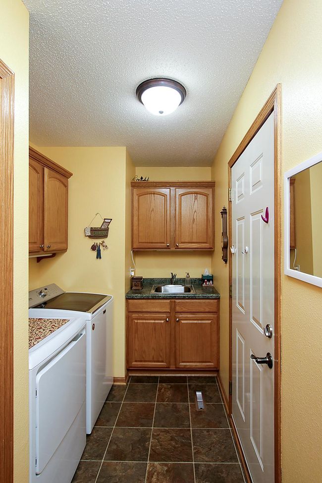 The laundry room features oak cabinets for additional storage. | Image 10