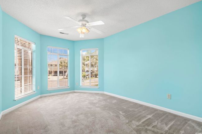 Carpeted empty room with a textured ceiling, a ceiling fan, and baseboards | Image 23