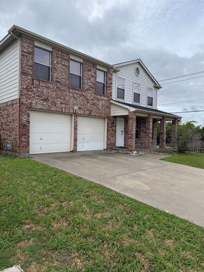View of front of property featuring an attached garage, concrete driveway, brick siding, and a front lawn | Image 28