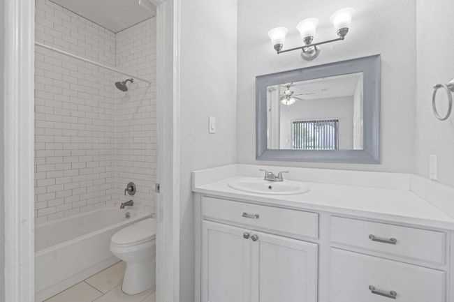 Bathroom featuring toilet, ceiling fan, tile patterned floors, vanity, and bathtub / shower combination | Image 15