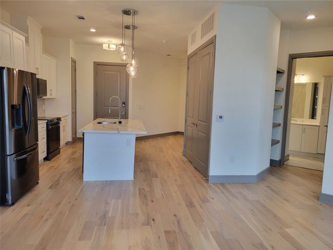 Kitchen featuring fridge with ice dispenser, black / electric stove, recessed lighting, light countertops, and a kitchen island with sink | Image 4