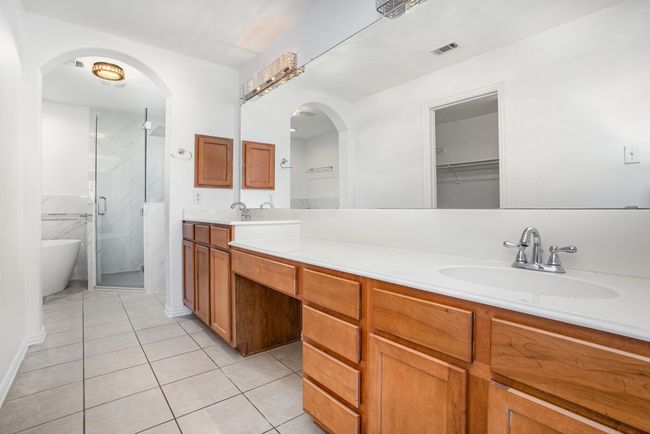 Primary Bedroom featuring a shower stall, tile patterned floors, double vanity and double sink. | Image 21