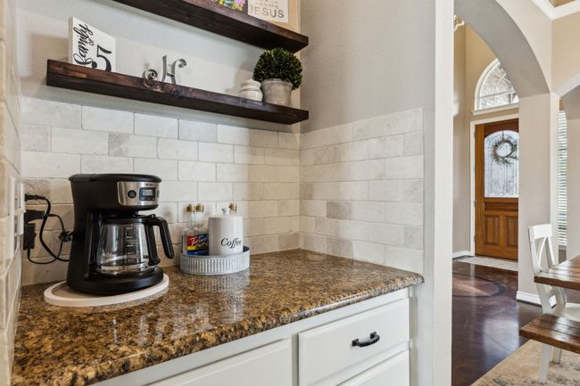 Butlers pantry featuring open shelves, decorative backsplash, granite countertops, and white cabinetry | Image 15