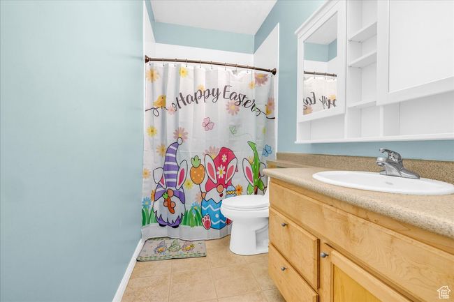 Full bath featuring a shower with shower curtain, toilet, tile patterned flooring, and vanity | Image 23