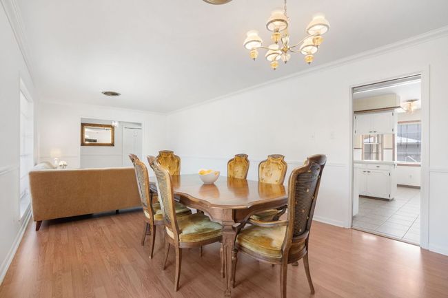 Formal Dining Room with a chandelier, crown molding, and laminate flooring. There's a pocket door in-between the dining room and the kitchen. | Image 6
