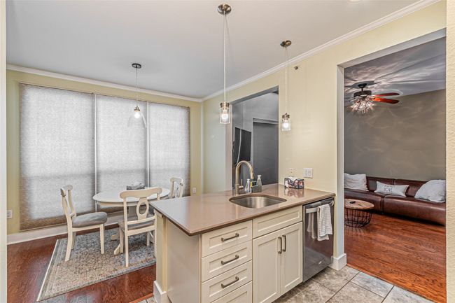 Kitchen featuring dishwasher, white cabinets, ceiling fan, ornamental molding, and hanging light fixtures | Image 14