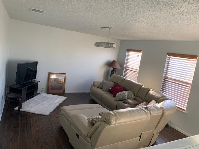 Living area with dark wood finished floors, a textured ceiling, and baseboards | Image 24