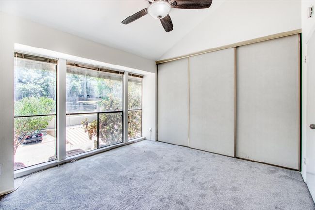 Unfurnished bedroom with carpet flooring, vaulted ceiling, a closet, and ceiling fan | Image 24