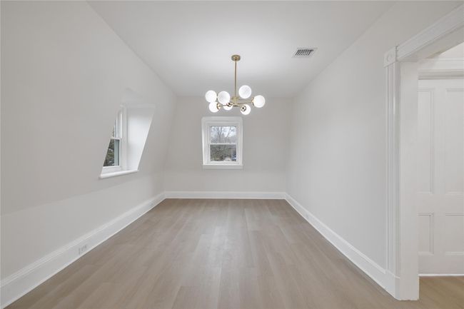 Unfurnished dining area featuring visible vents, light wood-style flooring, an inviting chandelier, and baseboards | Image 8