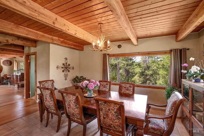 Tiled dining room with a wood ceiling with exposed beams, a chandelier, and plenty of natural light | Image 16