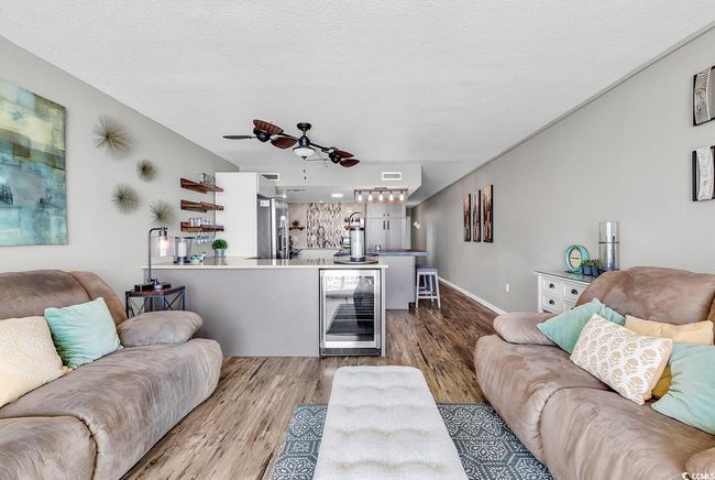 Living room with wine cooler, a textured ceiling, visible vents, a ceiling fan, and wood finished floors | Image 24