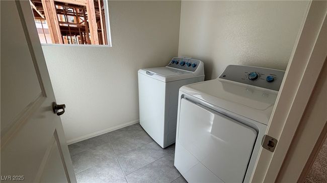 Clothes washing area with washing machine and dryer, baseboards, light tile patterned flooring, and laundry area | Image 14
