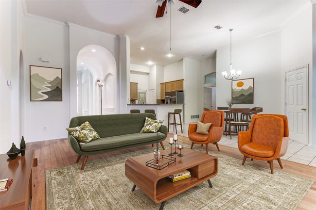 Living area featuring light wood-type flooring, a ceiling fan, a high ceiling, a chandelier, and ornamental molding | Image 12