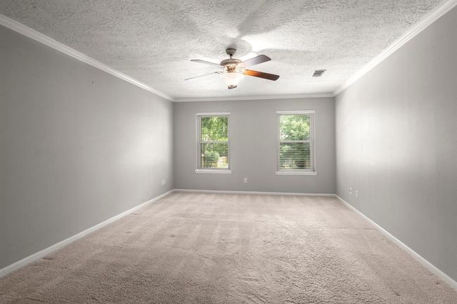 Plush carpet with thick padding, a ceiling fan for year-round comfort, elegant crown molding, and a restful color palette all come together to make this primary suite a true retreat. | Image 25