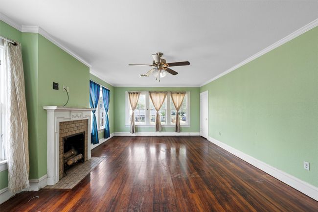 Unfurnished living room with crown molding, wood-type flooring, a fireplace, and a ceiling fan | Image 24