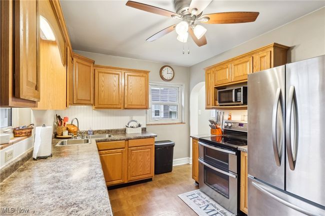 Kitchen with a sink, ceiling fan, arched walkways, stainless steel appliances, and light countertops | Image 11