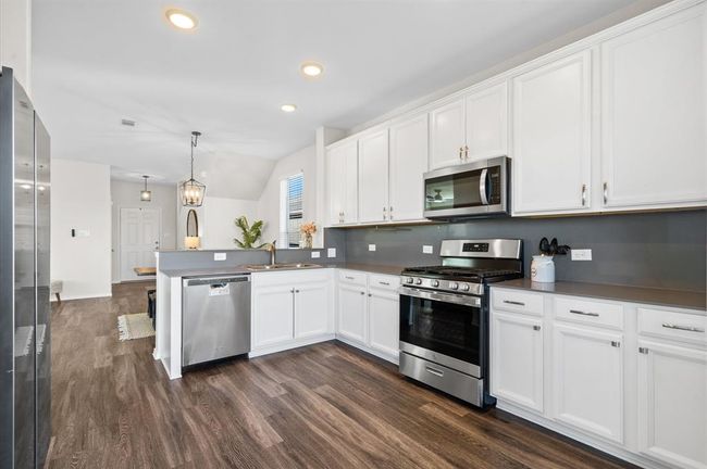 Cabinets offer brush nickel hardware, and updated faucet and quartz countertop and backsplash. | Image 11