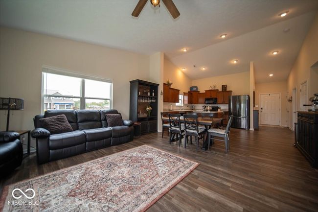 living area featuring dark vinyl flooring with wood appearance and vaulted ceiling | Image 10