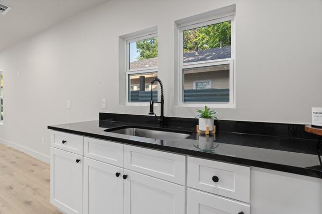 Kitchen featuring a sink, light wood-type flooring, white cabinets, baseboards, and dark stone counters | Image 8