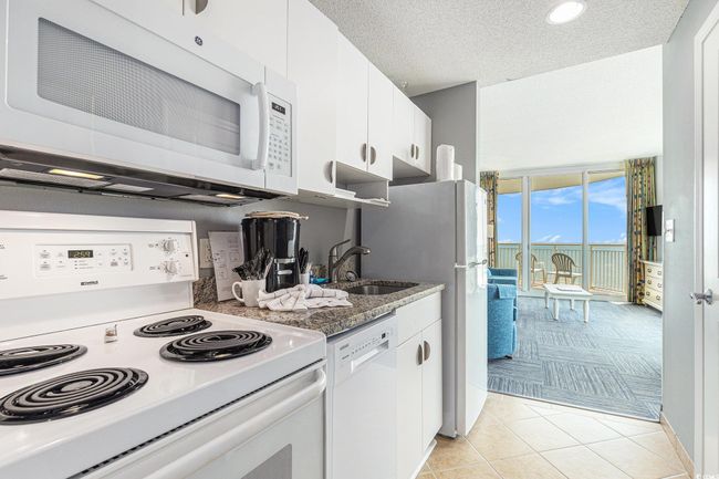 Kitchen with white appliances, a sink, light carpet, white cabinets, and light tile patterned floors | Image 9