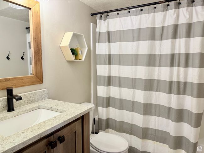 Full bath featuring toilet, a textured ceiling, curtained shower, and vanity | Image 41