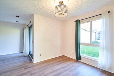 Unfurnished room featuring a barn door, hardwood / wood-style flooring, a textured ceiling, and a wealth of natural light | Image 3