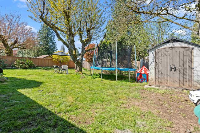 View of yard with a storage unit, an outdoor structure, a fenced backyard, and a trampoline | Image 25