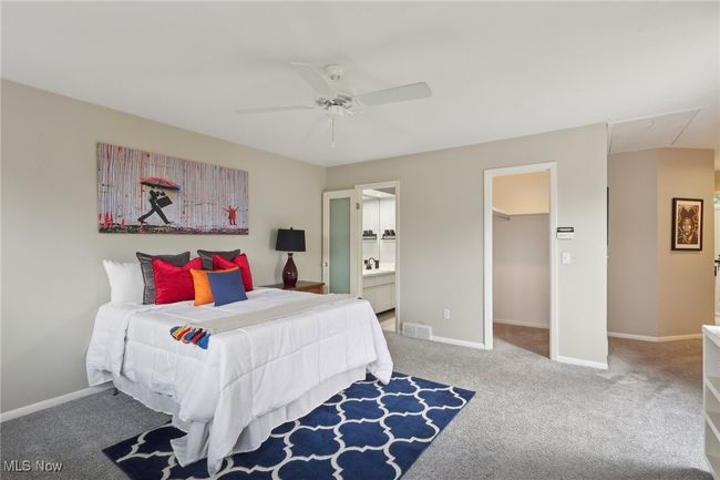 Carpeted bedroom with ensuite bath, ceiling fan, a spacious closet, and baseboards | Image 26
