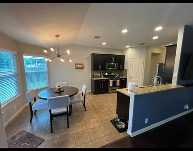 Kitchen with stainless steel appliances, a chandelier, dark cabinets, light tile patterned flooring. | Image 6
