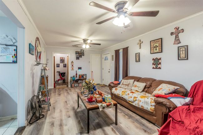 Living room with crown molding, light wood-style flooring, baseboards, and ceiling fan | Image 8