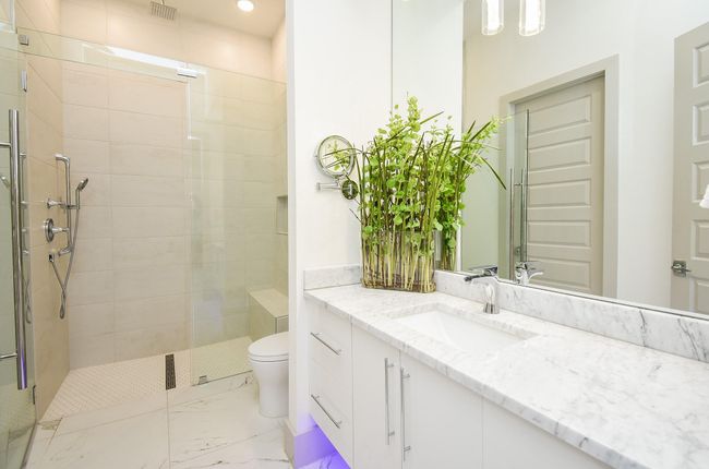 Light and bright secondary bathroom with frameless walk-in shower and Carrarra white countertops. | Image 37