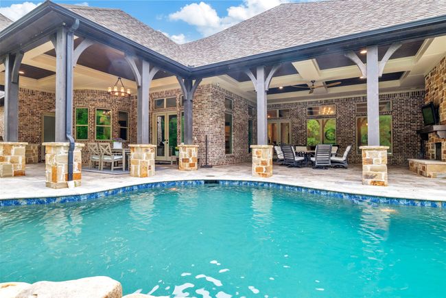You won't need to spend money on vacations when you have two enormous covered patios to relax on! One has a stone fireplace and the other a stone outdoor kitchen! All within easy splashing distance from the pool. | Image 29