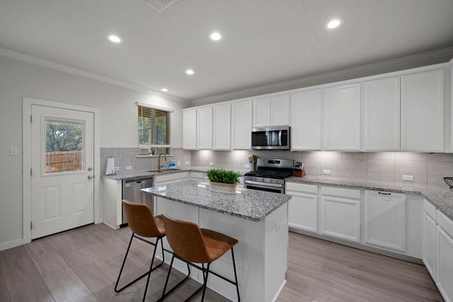 Kitchen featuring ornamental molding, stainless steel appliances, a center island, a sink, and light wood finished floors | Image 5