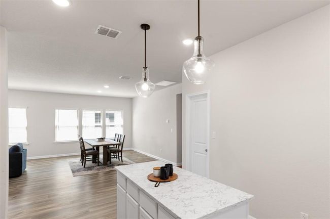 Kitchen featuring pendant lighting, wood finished floors, a center island, open floor plan, and visible vents | Image 18