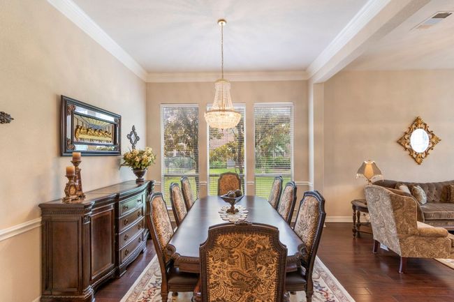 Dining area with a chandelier, dark wood-style floors, ornamental molding, and baseboards | Image 9
