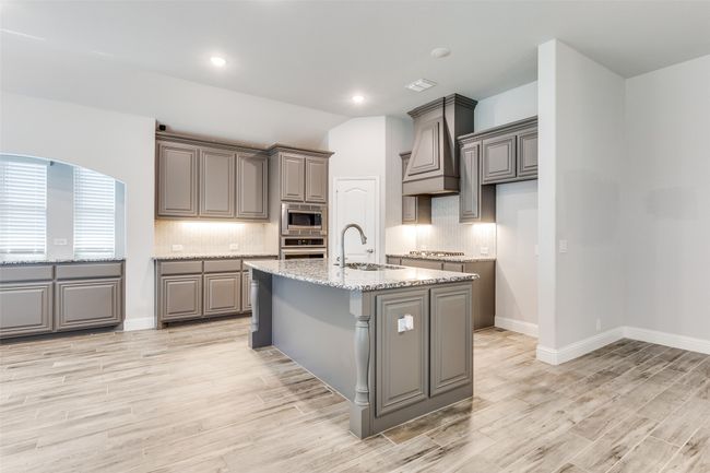 Kitchen featuring gray cabinets, stainless steel appliances and an island. | Image 10